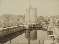 De sluis met links het landje van top en de Drommedaris omstreeks 1870. De brede brug en het huis naast de brug met overhellende overdekte balkons, zijn op deze foto nog aanwezig.