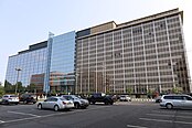 A photo of a building whose left side is blue glass, and right side is brown