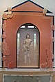 Photographie d'un petit autel en forme de niche renfermant une statuette.