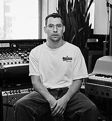 A black and white picture of a man sitting in a music studio.