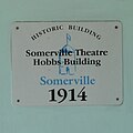 The historical marker sign on the face of the Somerville Theatre Hobbs Building