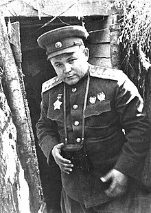 Photographie en noir et blanc d'un général dans une tranchée.