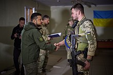 Zelenskyy awarding a soldier near the front line in the Kharkiv Oblast Robocha poyizdka Prezidenta Ukrayini na Kharkivshchinu 24.jpg