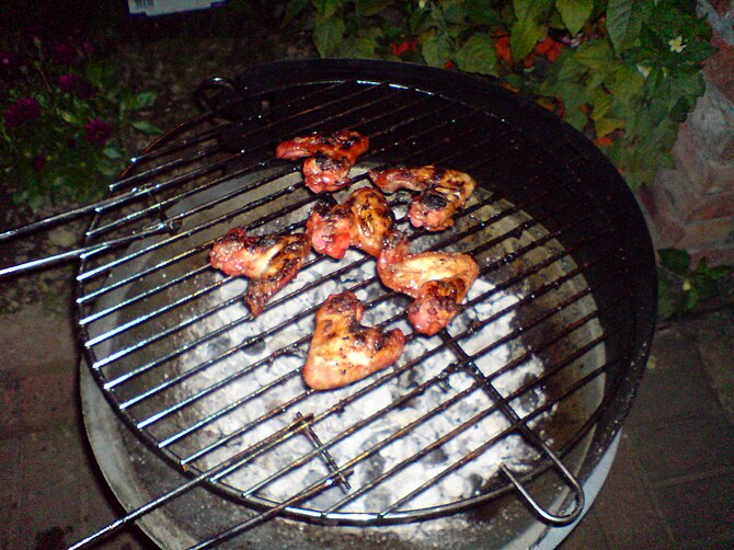 English: Chicken wings being cooked slowly ove...