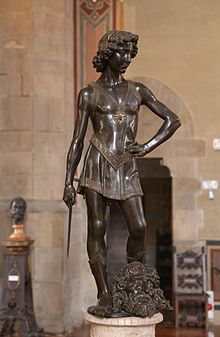 Bronze statue of a young man with a head at his feet