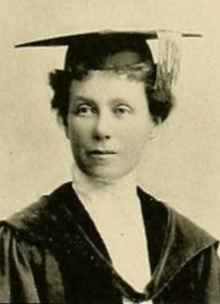 A white woman wearing academic robes and a mortarboard cap