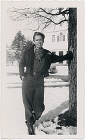 Pauli Murray steht an einen Baum gelehnt und schaut leicht blinzelnd in die Kamera. Sie trägt eine Hose, eine kurz geschnittene Jacke und ein gepunktetes Halstuch.