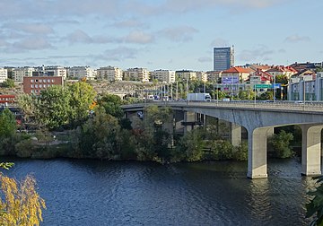 Till vänster syns Stora Essingebron kort före rivningen 1963, i bakgrunden pågår byggarbetena för Essingebron. Till höger visas samma vy från Essingeringen i oktober 2020.