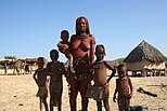 Himba emakume bat eta bere familiko batzuk zutik bere aitaren etxean Otutatin, Kunene Eskualdean, Namibia.