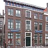 Roode Steen 16: Huis met monumentale bakstenen gevel van vijf traveeën, afgesloten door klassiek hoofdgestel met metopen en triglyphen