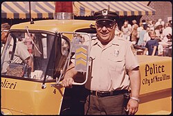 Parking meter checker stands by his police vehicle which is imprinted with the German word for police (Polizei
). It is part of the town's highlighting its German ethnic origins. New Ulm, Minnesota, July 1974. New ulm police.jpg
