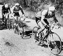 Photo en noir et blanc montrant trois cyclistes à vélo.