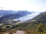 Von einer Anhöhe herunter aufgenommenes Foto einer am inneren eines Fjordes gelegenen Ansiedlung