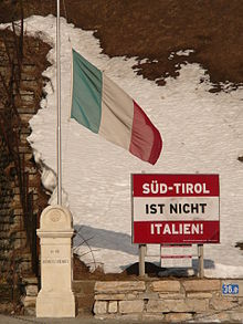 Poster saying "South Tyrol is not Italy!" on the background of an Austrian flag. The poster is located on the Austrian side of the border, not in South Tyrol. Suedtirol ist nicht Italien - Brennero.JPG