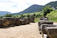 Photographie en couleurs de blocs de pierre alignés sur deux rangées au sol.