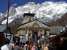 A temple building made in stone and ice capped mountains seen in background.