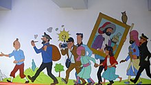 Tintin is standing in a group amongst the main characters of the comics series.