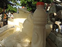 A bottle of suero costeño in foreground and costeño cheese in background at a market stand in Barranquilla.