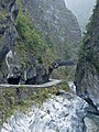 Ciclisti e moto su una stretta strada lungo le montagne