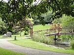 a path leading to a wooden bridge over a pond