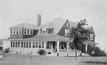 Image of the exterior of the Inverness Club House, with people seated on porch stairs, in 1910.