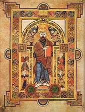 Page en vélin portant une riche enluminure représentant Jésus-Christ au centre entouré de quatre personnages plus petits, probablement les Évangélistes. L'ensemble est décoré de motifs celtiques colorés.