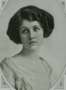 A young white woman's face and upper torso, in an oval frame. Her dark wavy hair is arranged at chin length, and she is wearing a light-colored dress with a scooped neck.