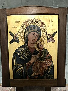 Dans un cadre en bois, icône représentant une femme avec une couronne et une auréole portant un bébé. Au-dessus de ces personnages, deux anges tenant une croix orthodoxe et un vase. L'arrière-plan est doré et agrémenté de quelques lettres en alphabet grec.