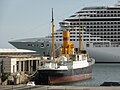 Amarrado en el puerto. Al fondo vemos la sección de proa del moderno buque de cruceros MSC Fantasia.