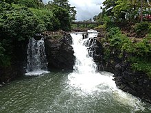 Falefa Falls, ein zweigeteilter Wasserfall mit einem großen Becken mit grünlichem Wasser in üppiger Vegetation.