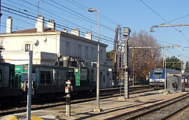 Rognac railway station, with a passing freight train and an Intercity-TER