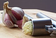 Garlic being crushed using a Garlic press.