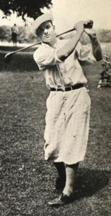 A young white man in a golf swing pose, wearing short loose trousers typical of a 1920s golf costume