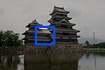 Structure à deux étages reliant une tour du château à trois étages avec une tour à cinq étages. Les trois structures ont des murs en bois noir et sont situés sur une plate-forme de pierres non taillées au-dessus d'un fossé rempli d'eau.