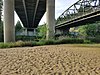 Небольшой песчаный речной пляж с бетонными мостами над головой.