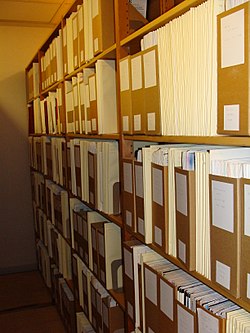 An archive of material including boxes, folders, and periodicals that take two shelves of six levels each