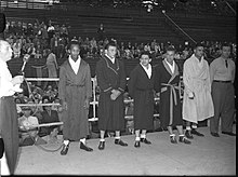 Des boxeurs en peignoirs se tiennent debout sur un ring de boxe.