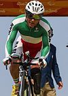Male cyclist in the Uniform of the Iranian Paralympic Team riding a bicycle