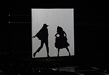 Silhouettes of a man and a woman are shown on a white screen.