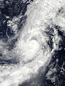 Satellite image of Hurricane Oho with a small, cloud-filled eye on October 6, with a large mass of clouds extending to the north of the hurricane.