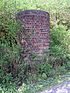 A cylindrical brick structure almost surrounded by vegetation.