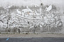 Cette fresque de reverse graffiti représente un radeau glonfable sur un torrent, avec à son bord les animaux des montagnes pyrénéennes.