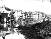 Photo en noir et blanc de maisons d’apparence modeste bordant une rivière