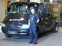A Certis CISCO auxiliary police officer beside an armoured truck at Change Alley CISCO Security.jpg