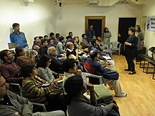 classroom full of people and a woman standing at the front talking