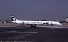 A white aircraft with the word "Alaska" on its side seen on a black airport tarmac