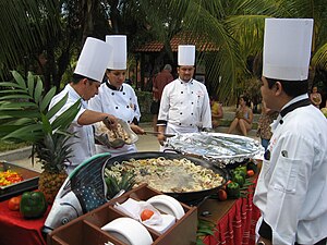 English: Chefs preparing a seafood paella in P...