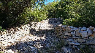 Chemin en garrigue, bordé de murs de pierres à Claret.