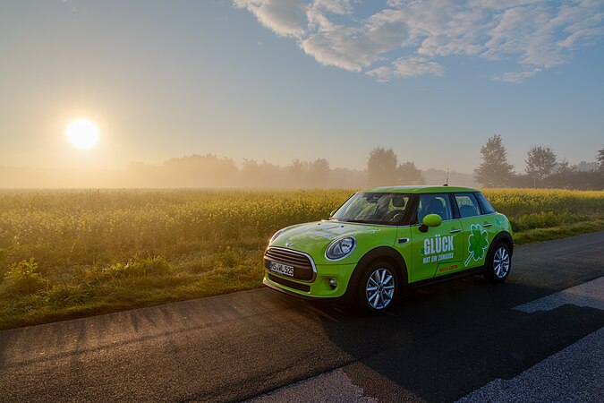 图为朝阳下行驶在德国北威州迪尔门乡间小路上的宝马迷你车。