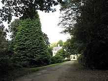 a view of the driveway to Presaddfed Hall with the hall partly obscured by trees.